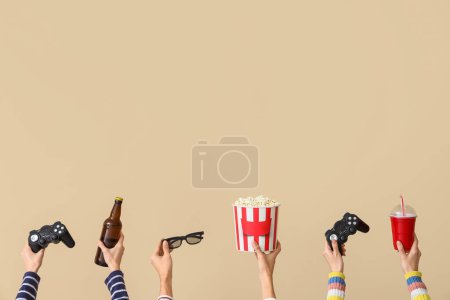 Photo for Many hands with bucket of popcorn, drinks and game pads on beige background - Royalty Free Image