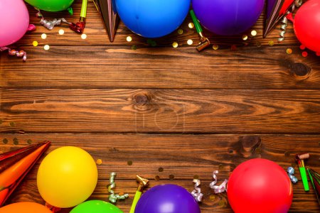 Téléchargez les photos : Cadre en ballons, bruyants et confettis sur fond bois - en image libre de droit