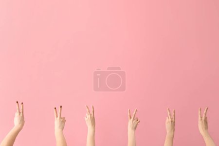 Téléchargez les photos : Mains féminines montrant des gestes de paix sur fond rose - en image libre de droit