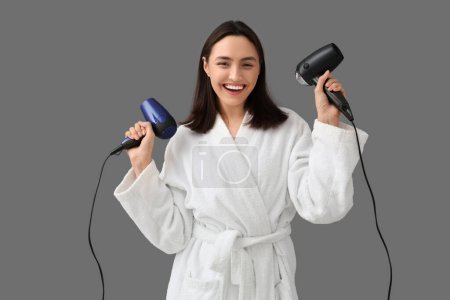 Photo for Beautiful young woman with hair dryers on grey background - Royalty Free Image