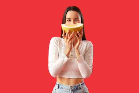Young woman with pomelo slice on red background