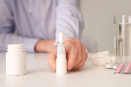 Téléchargez les photos : Homme d'affaires malade avec des gouttes nasales et des pilules sur la table au bureau, gros plan - en image libre de droit