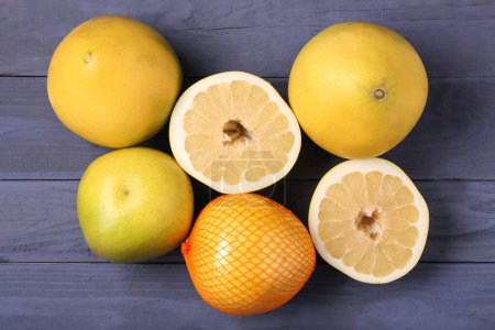 Foto de Sabrosos frutos de pomelo enteros y cortados sobre fondo de madera azul - Imagen libre de derechos