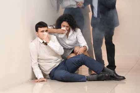 Téléchargez les photos : Des hommes d'affaires aux visages couverts étouffés par la fumée dans un immeuble de bureaux en feu - en image libre de droit