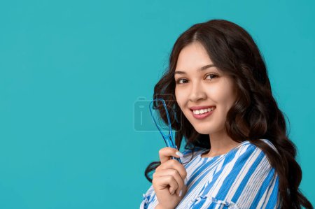 Téléchargez les photos : Heureuse jeune femme asiatique avec grattoir de langue sur fond bleu - en image libre de droit