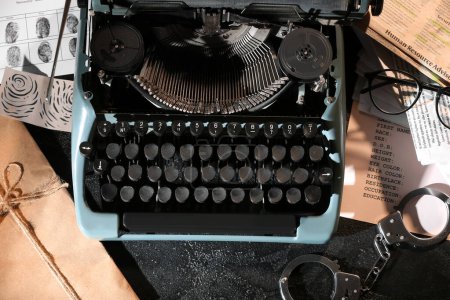 Máquina de escribir retro, esposas y archivos criminales en la mesa oscura