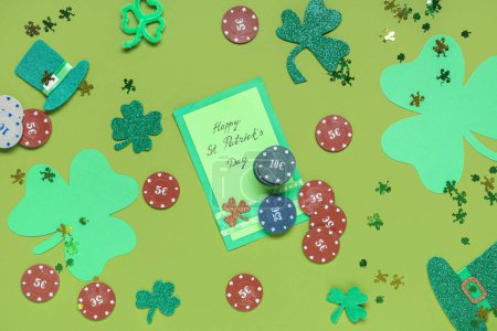 Composition with poker chips, clovers and greeting card on green background. St. Patrick's Day celebration