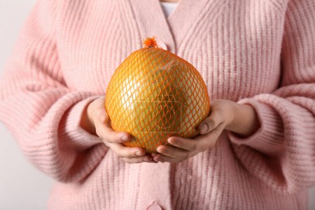 Foto de Mujer sosteniendo dulce pomelo en red sobre fondo blanco - Imagen libre de derechos