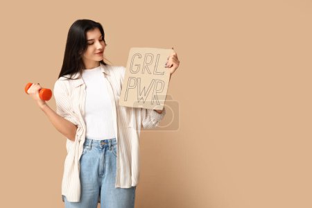 Young woman with dumbbell and sign GRL PWR on beige background. Feminism concept