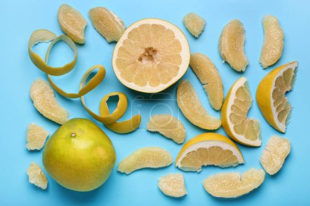 Foto de Sabrosos frutos enteros y cortados de pomelo con rodajas sobre fondo azul - Imagen libre de derechos