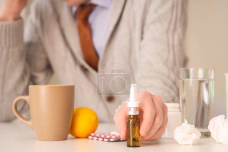 Téléchargez les photos : Homme d'affaires malade avec des gouttes nasales, citron et pilules sur la table au bureau, gros plan - en image libre de droit