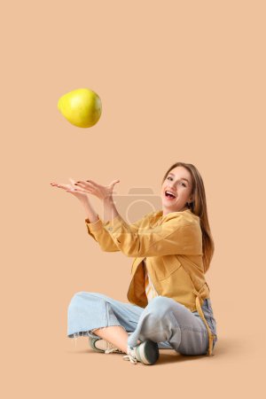 Foto de Mujer joven sonriente con pomelo sentado sobre fondo beige - Imagen libre de derechos