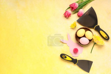 Composition with Easter eggs, flowers and building trowels on color background