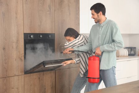 Young couple extinguishing fire in oven at home