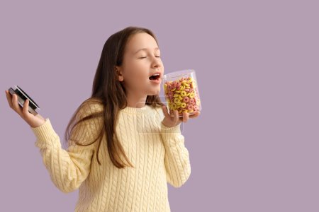 Petite fille mignonne avec pot de bagues de céréales sur fond lilas