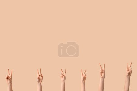 Téléchargez les photos : Mains féminines montrant des gestes de paix sur fond beige - en image libre de droit