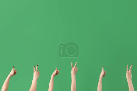 Téléchargez les photos : Mains féminines montrant la paix et les gestes du pouce sur fond vert - en image libre de droit