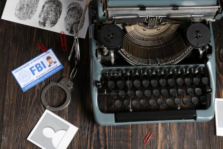 Máquina de escribir retro, esposas, documento del agente del FBI y huellas dactilares en mesa de madera