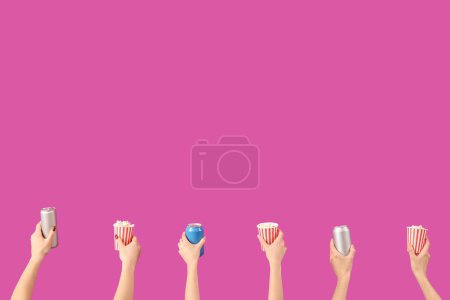 Hände halten Eimer mit Popcorn und Getränken auf rosa Hintergrund
