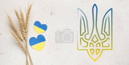 Hearts in colors of Ukrainian flag, wheat spikelets and coat of arms on light background