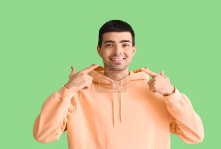 Téléchargez les photos : Jeune homme pointant son sourire sur fond vert - en image libre de droit