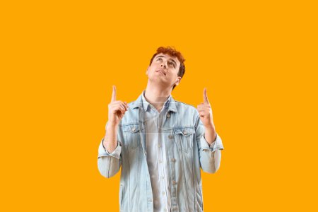 Photo for Young redhead man pointing at something on yellow background - Royalty Free Image
