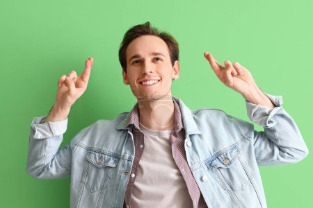 Photo for Young man pointing at something on green background - Royalty Free Image