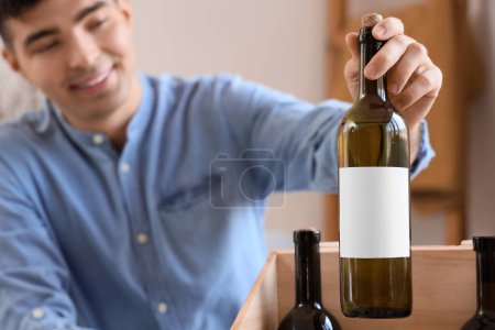 Photo for Young man with bottle of wine at home, closeup - Royalty Free Image