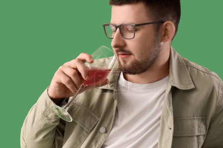Photo for Young sommelier tasting wine on green background, closeup - Royalty Free Image