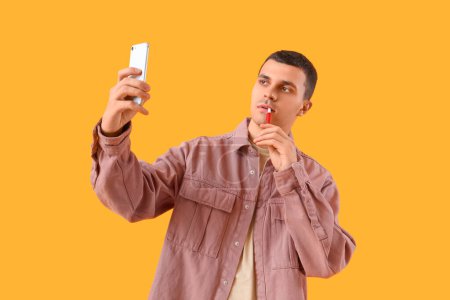 Téléchargez les photos : Jeune homme avec prise de cigarette électronique selfie sur fond jaune - en image libre de droit