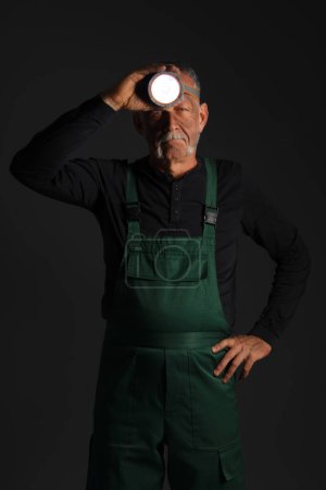 Mature miner man with headlamp on dark background