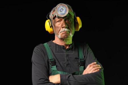 Mature miner man on black background, closeup