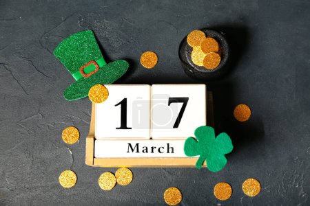 Photo for Leprechaun pot with golden coins and wooden calendar on black background. St. Patrick's Day celebration - Royalty Free Image