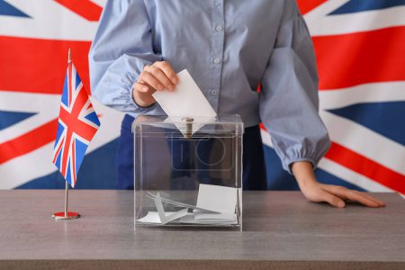 Junge Frau mit britischer Flagge in der Nähe der Wahlurne auf Tisch im Wahllokal