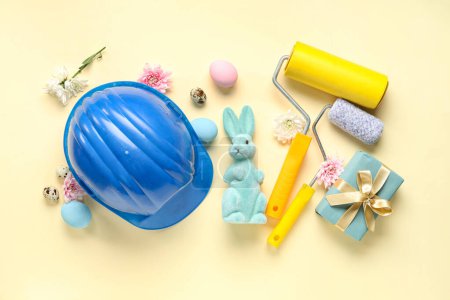 Foto de Composición con hardhat, rodillos de pintura, caja de regalo y decoración de Pascua sobre fondo de color - Imagen libre de derechos
