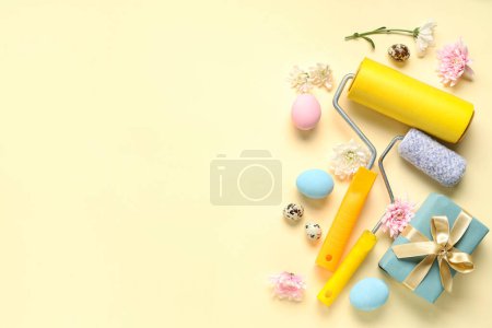 Foto de Composición con rodillos de pintura, caja de regalo, flores y huevos de Pascua sobre fondo de color - Imagen libre de derechos