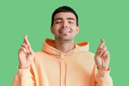Téléchargez les photos : Jeune homme croisant les doigts sur fond vert - en image libre de droit