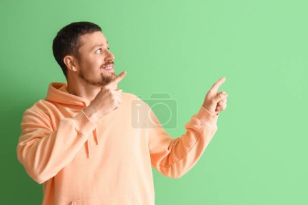 Téléchargez les photos : Bel homme pointant quelque chose sur fond vert - en image libre de droit