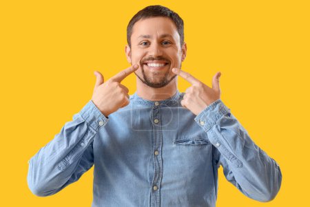 Téléchargez les photos : Beau homme pointant son sourire sur fond jaune - en image libre de droit