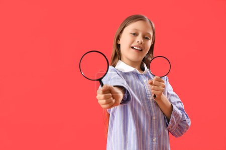 Little girl with magnifiers on red background