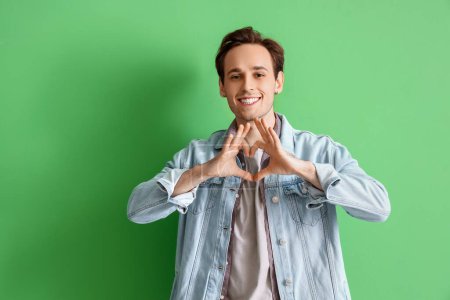 Téléchargez les photos : Jeune homme faisant geste de cœur sur fond vert - en image libre de droit