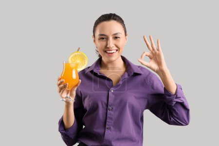 Female bartender with cocktail showing OK on light background