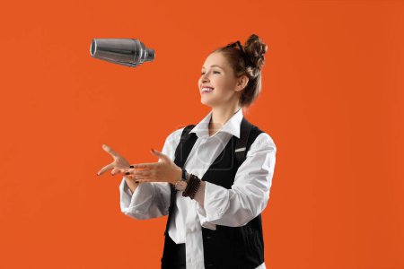 Female bartender with shaker on orange background