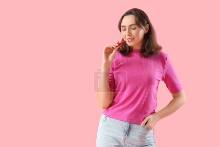 Téléchargez les photos : Jeune femme avec cigare électronique sur fond rose - en image libre de droit