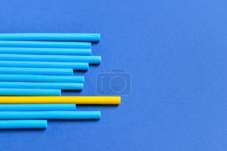 Téléchargez les photos : Un bâton jaune parmi les bleus sur fond de couleur. Concept d'unicité - en image libre de droit