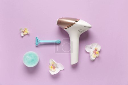 Photo for Modern photoepilator with razor, jar of scrub and orchid flowers on purple background - Royalty Free Image