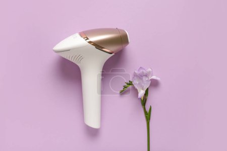 Photo for Modern photoepilator with beautiful flower on purple background - Royalty Free Image