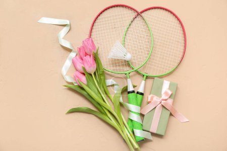 Téléchargez les photos : Composition avec raquettes de badminton, coffret cadeau et fleurs de tulipes pour la Journée internationale de la femme sur fond de couleur - en image libre de droit