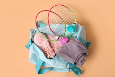 Téléchargez les photos : Sac de sport avec vêtements de sport, raquettes de badminton et chaussures sur fond beige - en image libre de droit