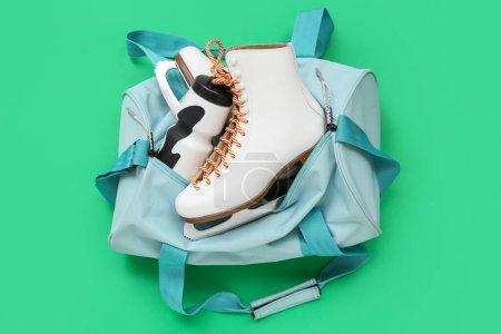 Sport bag with skates and headphones on green background